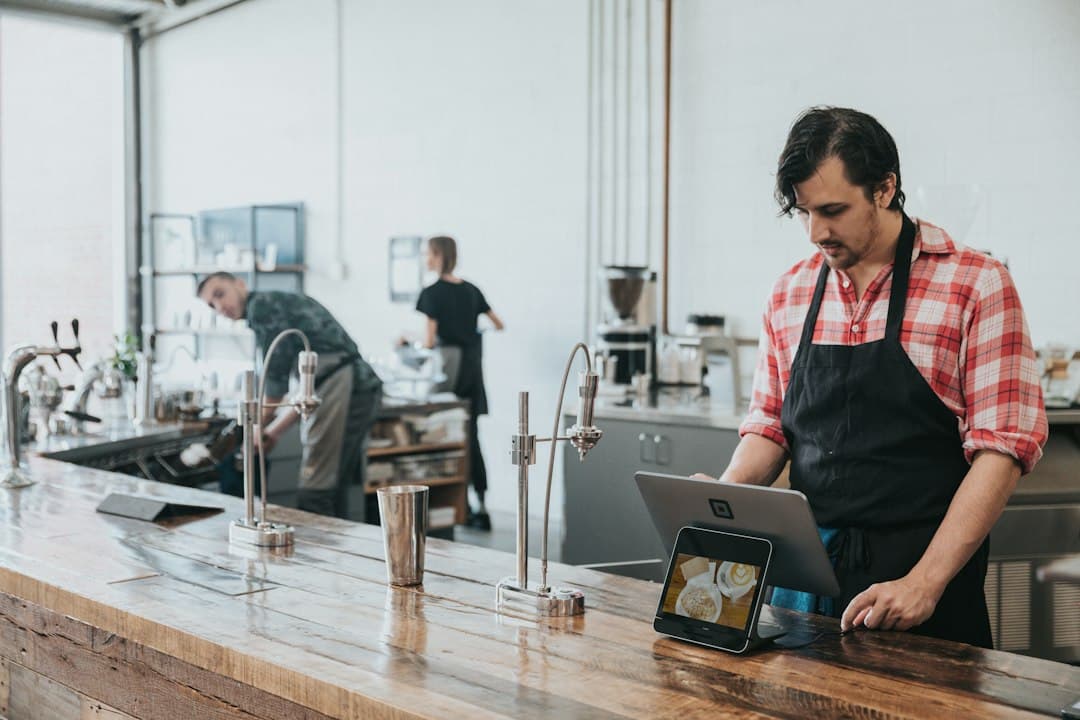 Barista using a tablet at a wooden café counter