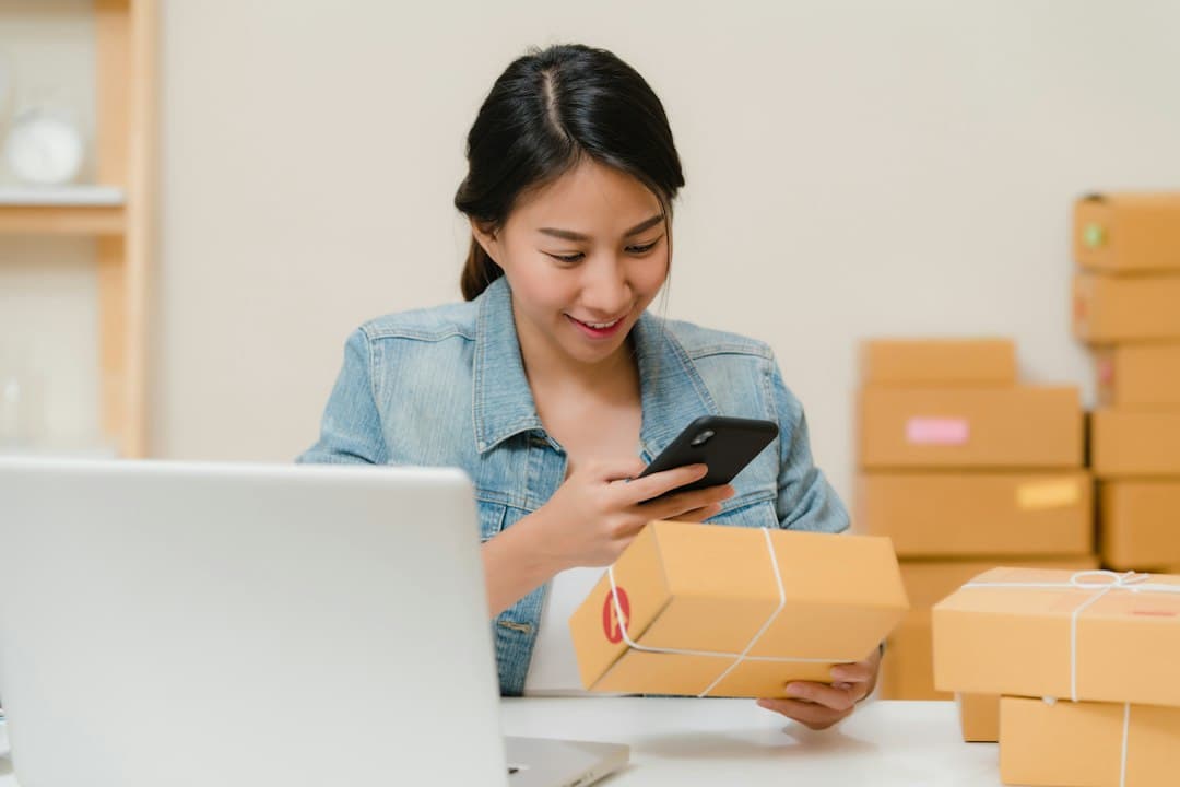 Online shop owner checking orders beside packed boxes